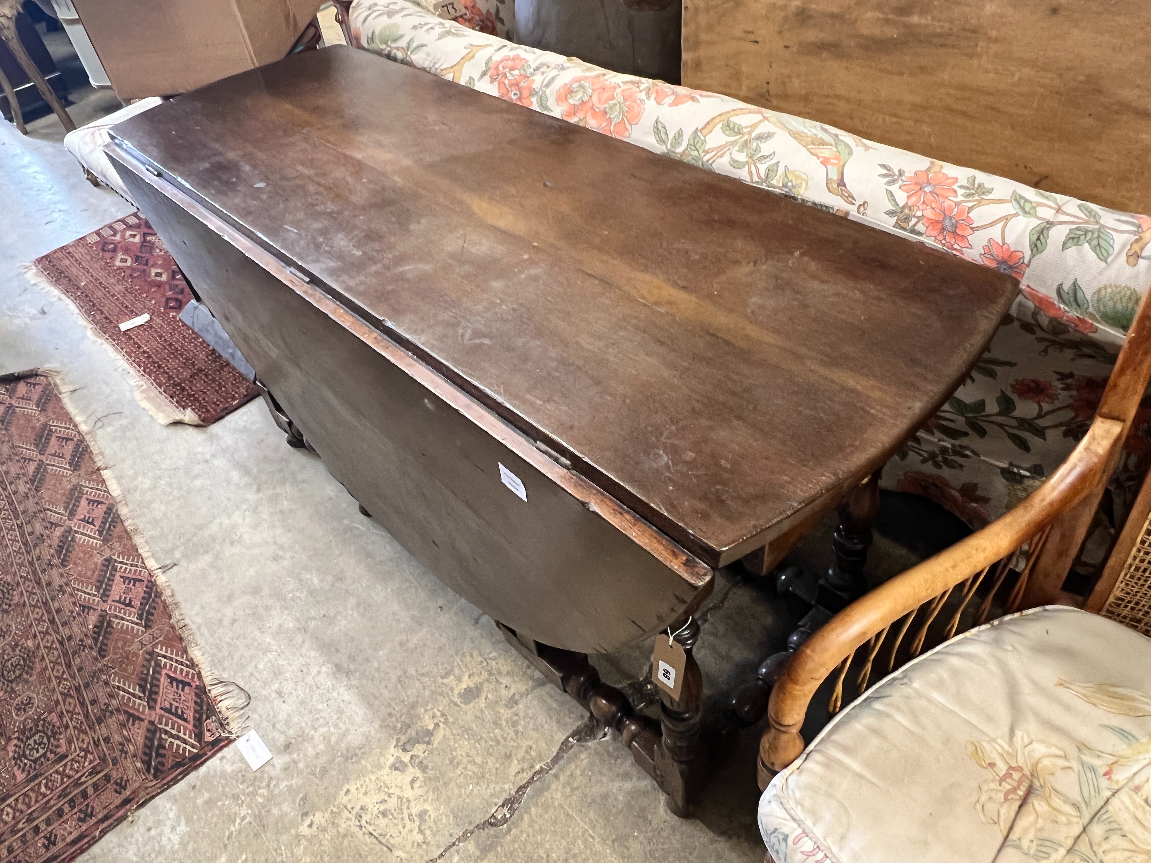 An early 18th century style oak oval topped gateleg dining table, (one leaf in need of repair), length 140cm, width 52cm, height 75cm